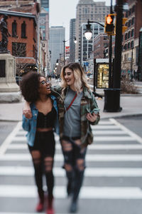 Cheerful friends crossing road in city