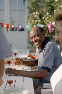 Portrait of smiling senior man sitting with woman at dining table in back yard
