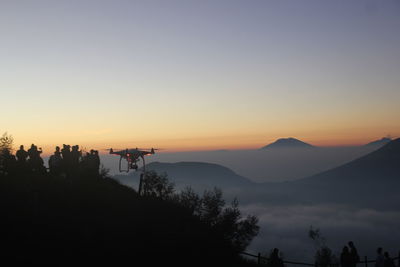 Silhouette people on mountain against sky during sunset