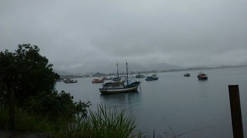 Boats in sea against cloudy sky