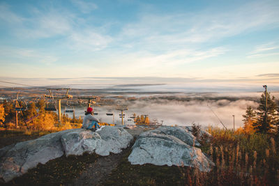 Hiker sits atop vuokatinvaara in sotkamo in the kainuu region, finland at sunrise