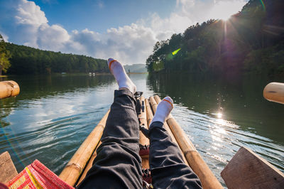 Low section of man relaxing on boat in lake