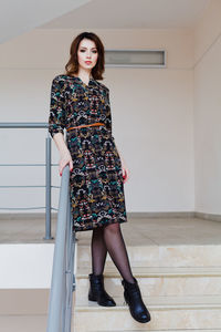 Portrait of young woman standing against wall