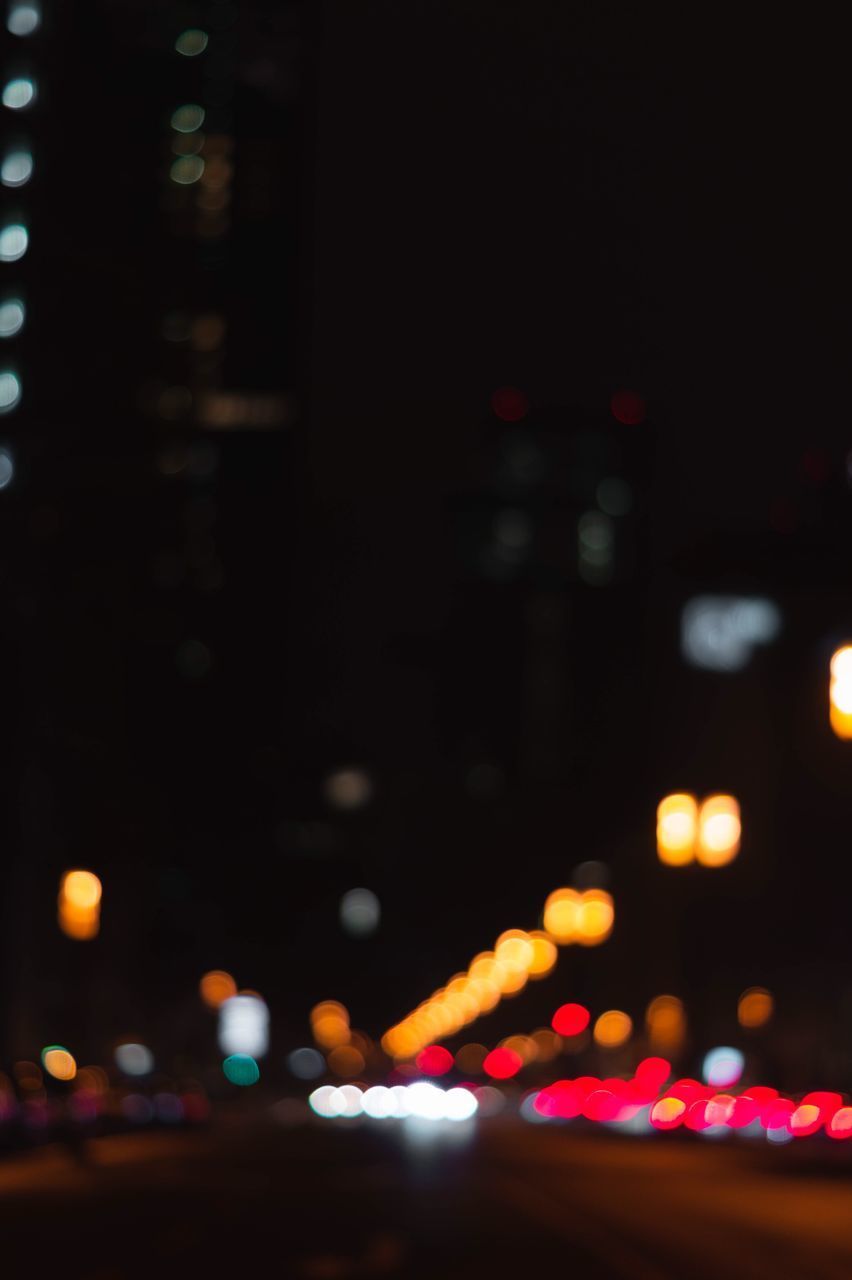 DEFOCUSED IMAGE OF ILLUMINATED CITY STREET AT NIGHT