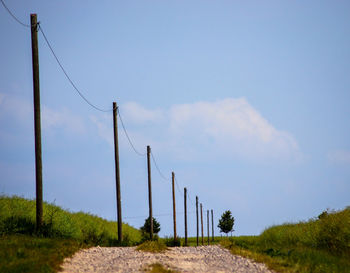 Low angle view of wooden posts on field against sky