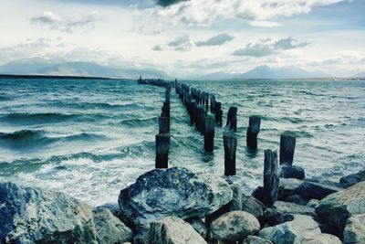 Poles on sea against sky