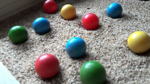 High angle view of multi colored marbles on sand