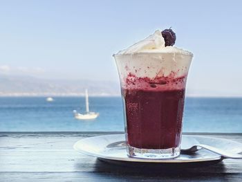 Close-up of drink on table by sea against sky