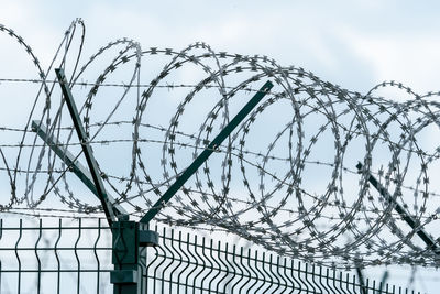 Low angle view of barbed wire against sky