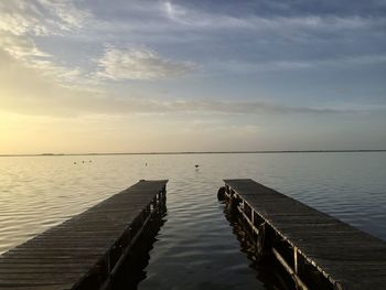 Pier over lake against sky during sunset