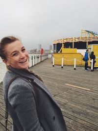 Portrait of happy woman standing at brighton pier against sky