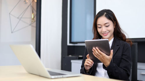 Businesswoman using digital tablet while sitting on table