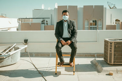 Full length portrait of young man sitting outdoors