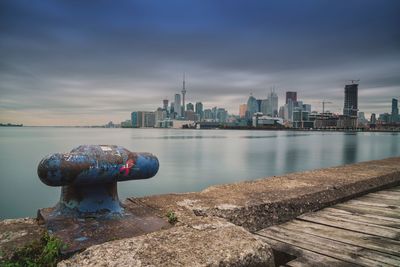 Cleat on pier by river in city against sky