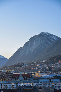 Townscape by mountains against clear blue sky