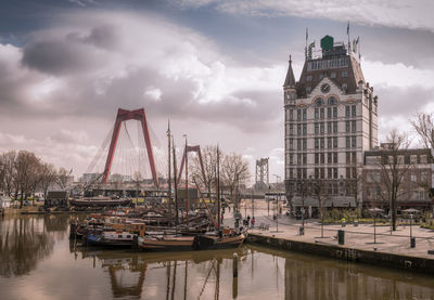 Sailboats in city against cloudy sky