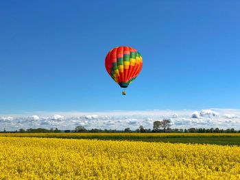 Scenic view of field with colorful balloon against sky