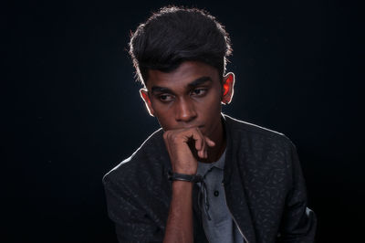 Portrait of young man against black background