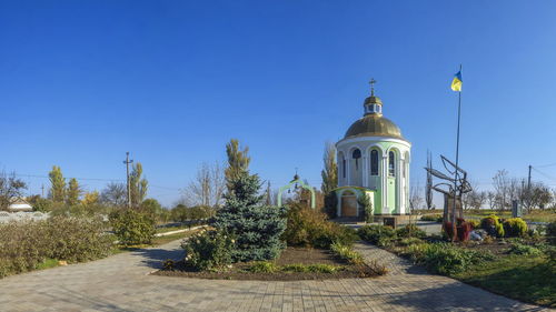 Plants by building against clear blue sky