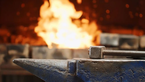 Close-up of hammer with anvil against fire