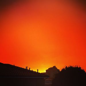 Silhouette built structures against orange sky