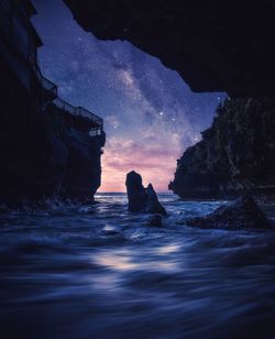 Silhouette rocks on sea against sky during sunset