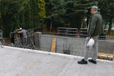 Foreman builder engineer worker looking at large building construction site sunny day hard work