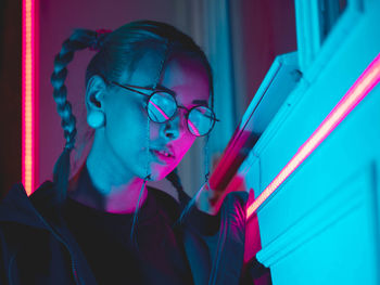 Close-up of young woman wearing eyeglasses while standing outdoors at night