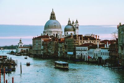 Boats in canal amidst buildings in city against sky