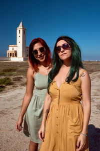 Young woman wearing sunglasses standing against clear sky