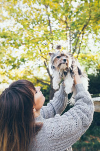 Woman with dog against trees