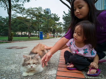 Portrait of girl with cat sitting outdoors