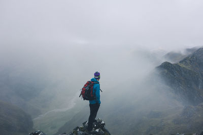 Man standing on cliff during foggy weather