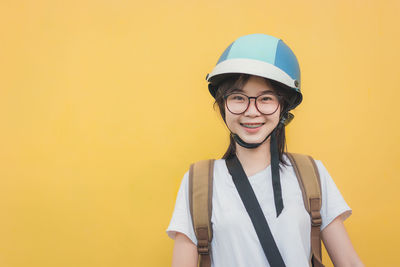 Portrait of smiling woman standing against yellow wall