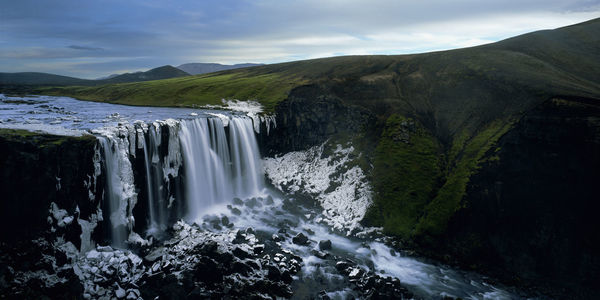 Scenic view of waterfall against sky