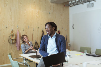 Smiling businessman and colleague at conference table in office