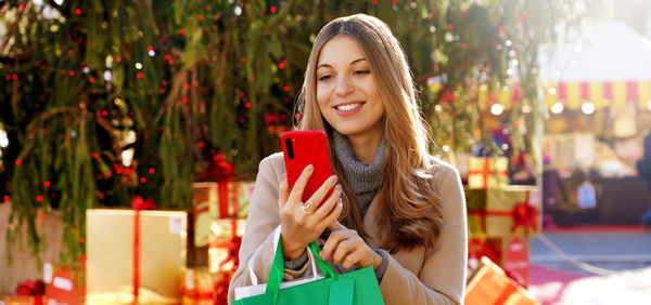 Woman receiving christmas wishes on smartphone when walking between christmas markets outdoors
