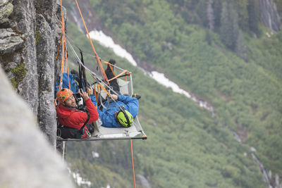 Portrait of rock climbers using portaledge during climbing trip.