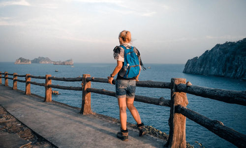 Rear view of woman walking by railing