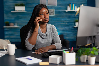 Young woman using mobile phone while sitting on table