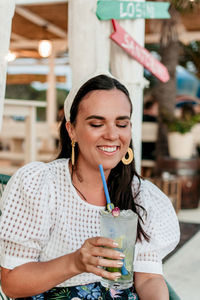 Portrait of a smiling young woman drinking glass