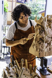 Sculptress carving wooden figure in the job