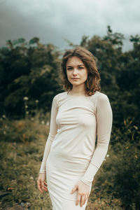 Portrait of young woman standing against plants