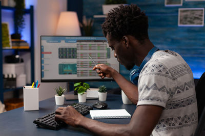 Side view of man using laptop at table