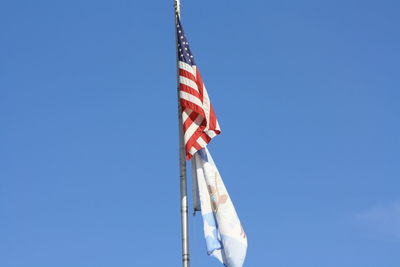 Low angle view of flags against clear blue sky