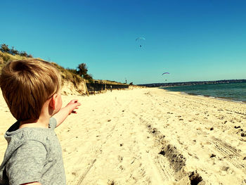 Baby boy pointing while standing at beach