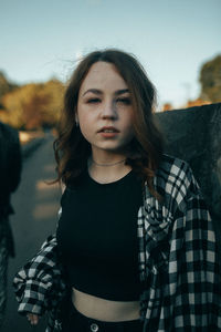 Portrait of young woman standing against sky