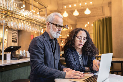 Mature couple using laptop in cafe