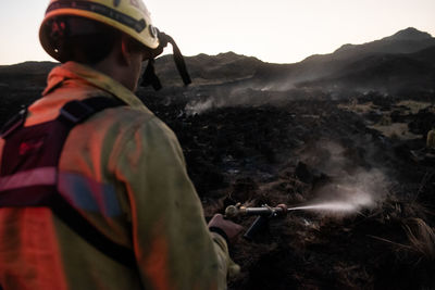 Rear view of firefighter extinguishing fire on mountain