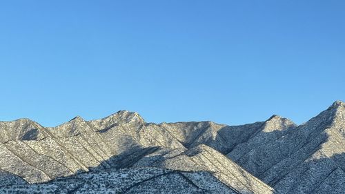 Low angle view of rocks against clear blue sky